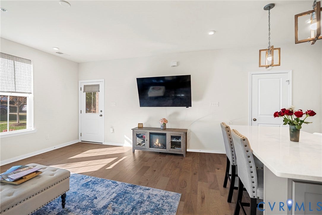 14501 Hancock Towns Drive, Chesterfield, VA 23832 Open-concept interior featuring wood-finish flooring, a quartz-topped island, rectangular multi-pane pendant lighting, and a door with an integrated glass window