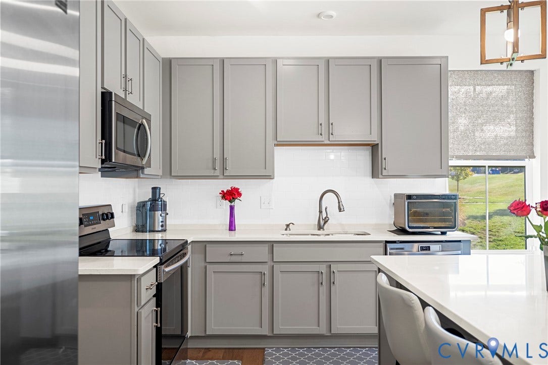 14501 Hancock Towns Drive, Chesterfield, VA 23832 Kitchen featuring grey shaker-style cabinetry, white solid-surface countertops, subway tile backsplash, stainless steel appliances, and a rectangular pendant light fixture