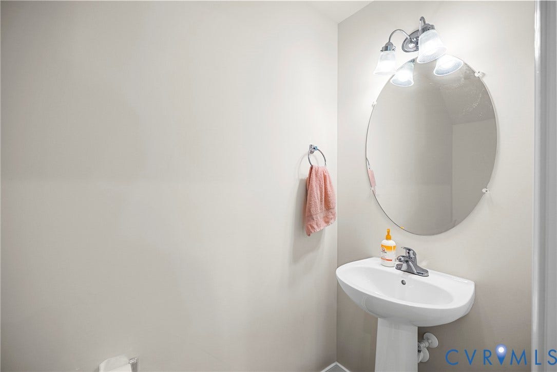 14501 Hancock Towns Drive, Chesterfield, VA 23832 Oval wall-mounted mirror, pedestal sink with chrome faucet, and three-light vanity fixture