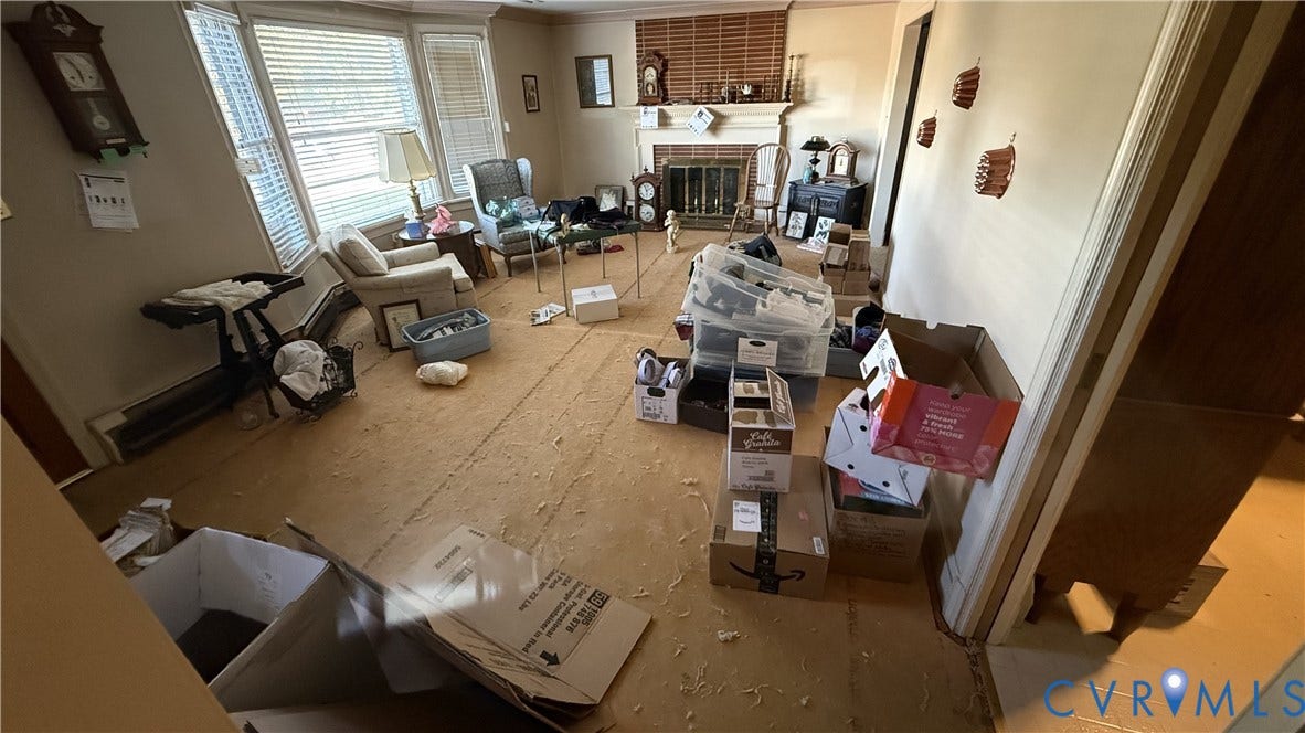 Living area featuring a bay window, masonry fireplace with a mantel, and carpeted flooring