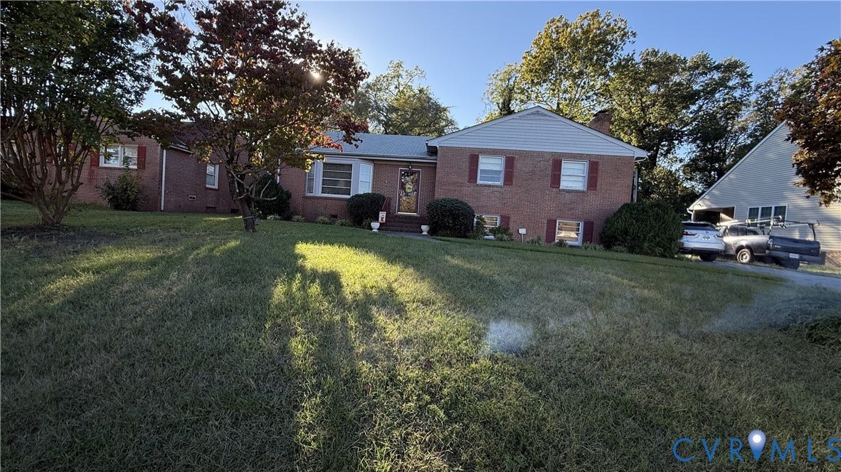 Brick exterior featuring a gabled roofline, light-colored siding, decorative shutters, and a detached garage