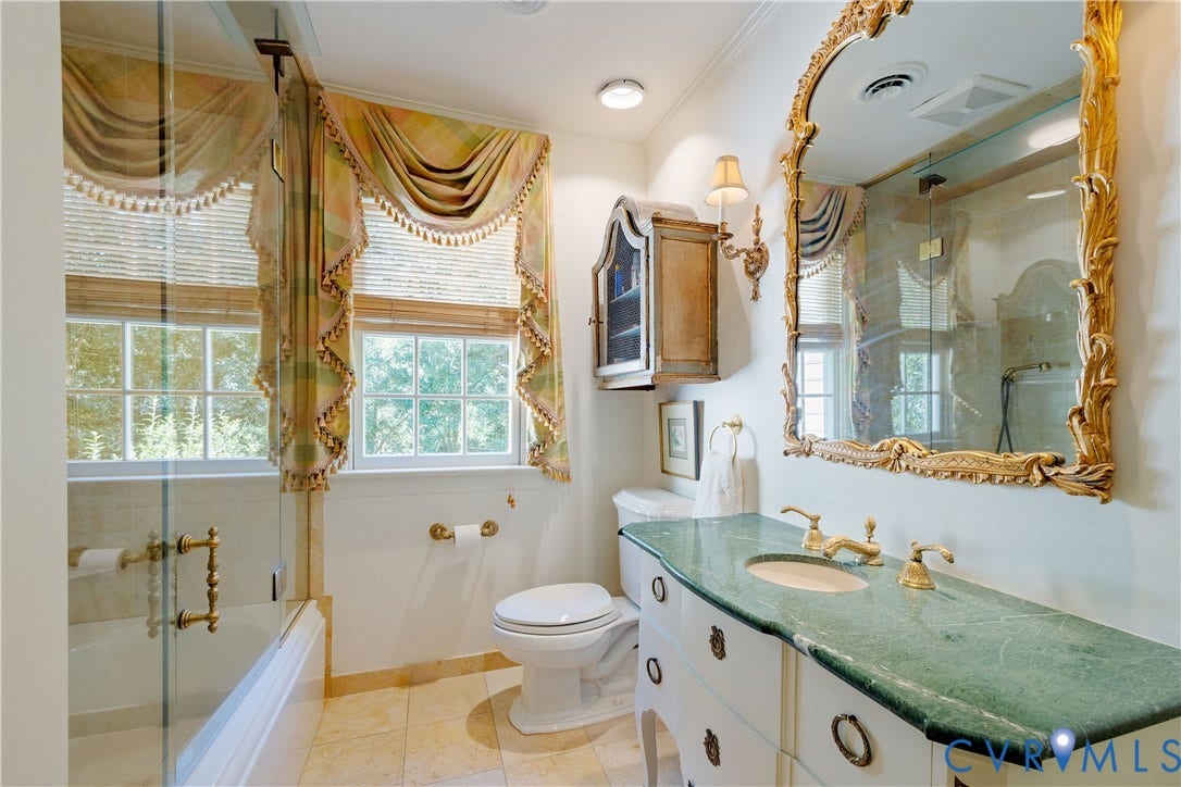 205 Poplar Lane, South Of Cary Street Rd, Richmond, VA 23226 The hall bath features a cabinet/vanity with oval undermount sink, brass-tone hardware, a glass-enclosed shower with a soaking tub, and tile flooring.