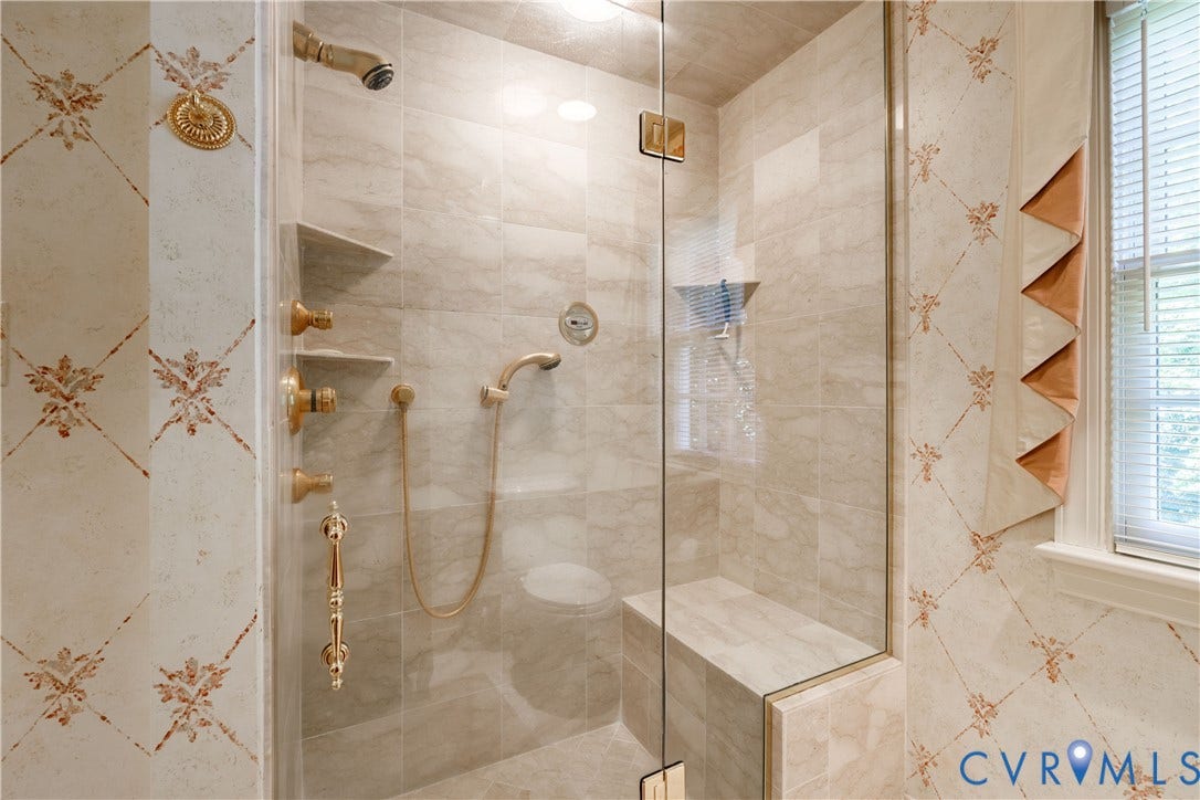 205 Poplar Lane, South Of Cary Street Rd, Richmond, VA 23226 Walk-in shower features floor-to-ceiling tile, brass-finish fixtures, a handheld showerhead, built-in bench seating, and a glass door enclosure.