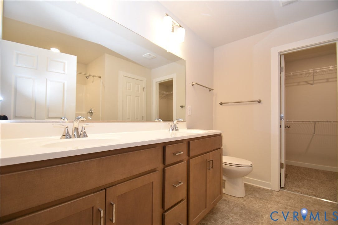 Lot 1 Bannister Town Road, Courtney Farms, Louisa, VA 23093 Dual-sink vanity with a solid-surface countertop, wood cabinetry, wall-to-wall mirror, and walk-in closet