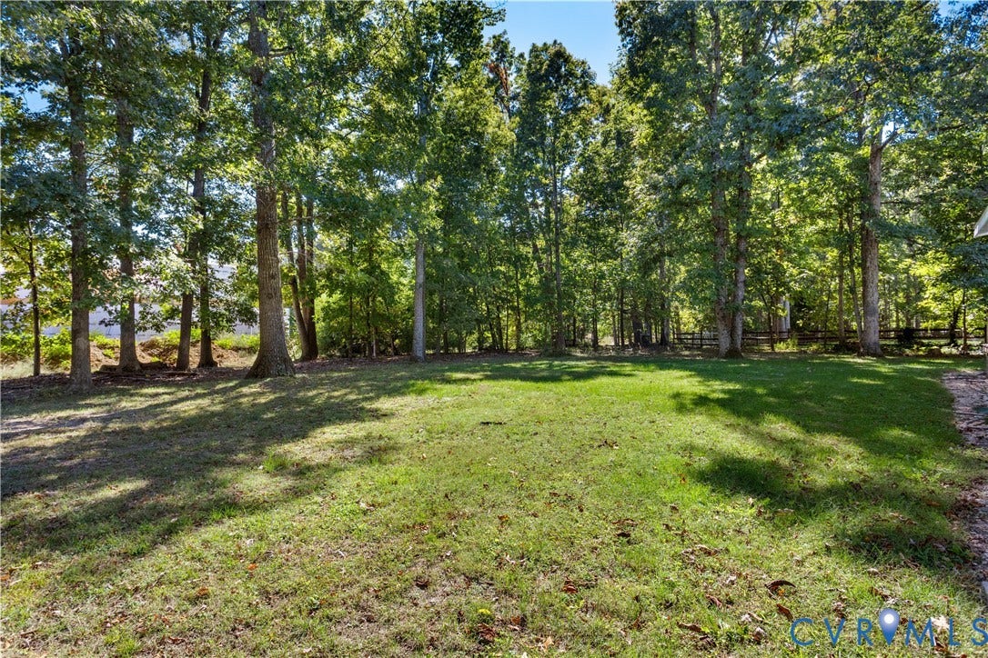 327 Huddersfield Drive, Chesterfield, VA 23236 Expansive backyard featuring a level grass lawn, mature trees, and wooden perimeter fencing