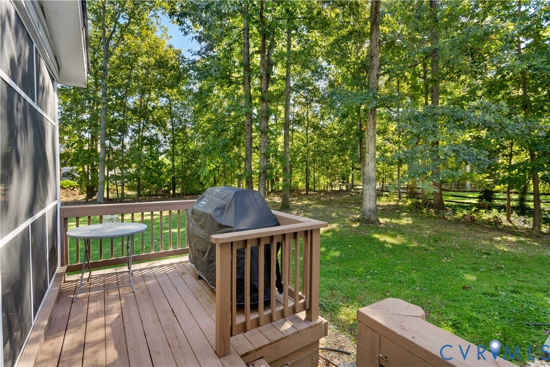 327 Huddersfield Drive, Chesterfield, VA 23236 Elevated wood-finished deck featuring a wooden balustrade, overlooking a private backyard with mature trees and a split-rail fence