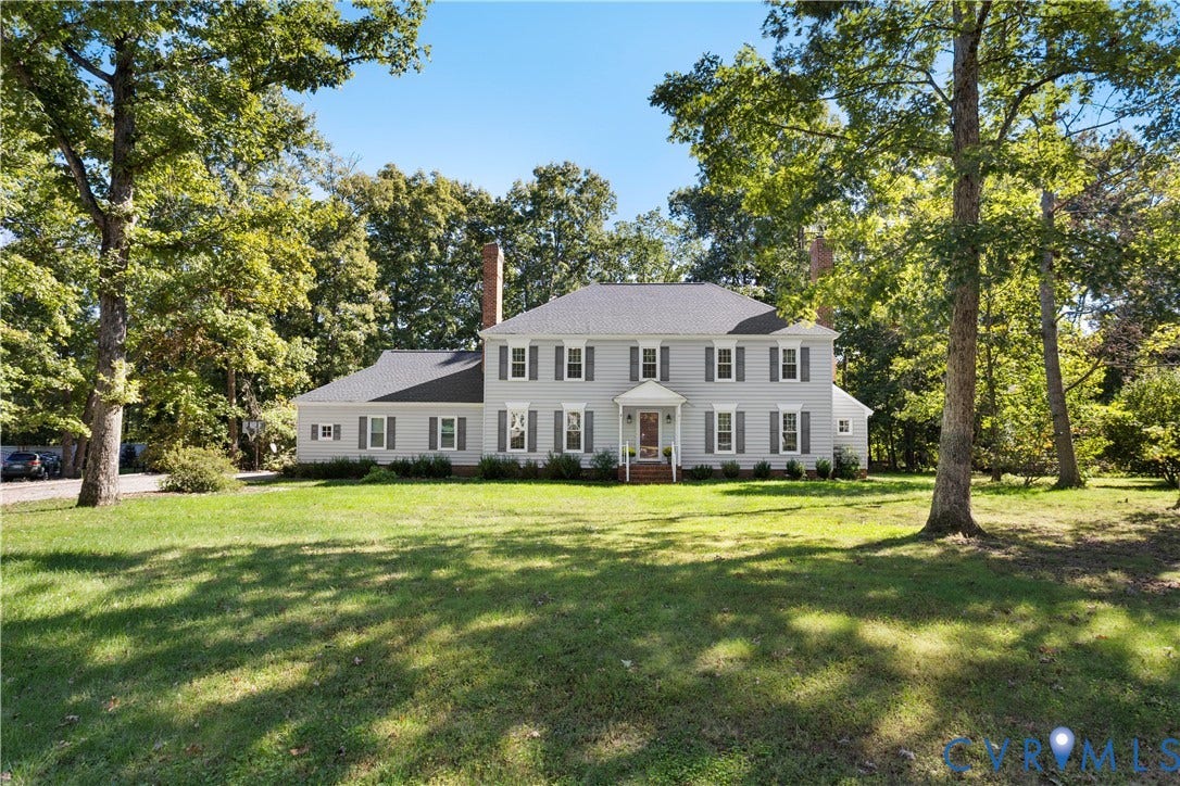 327 Huddersfield Drive, Chesterfield, VA 23236 Two-story traditional exterior featuring light-toned horizontal siding, a symmetrical faade with multi-pane windows, a covered front entryway, two brick chimneys, and a sprawling lot with mature trees