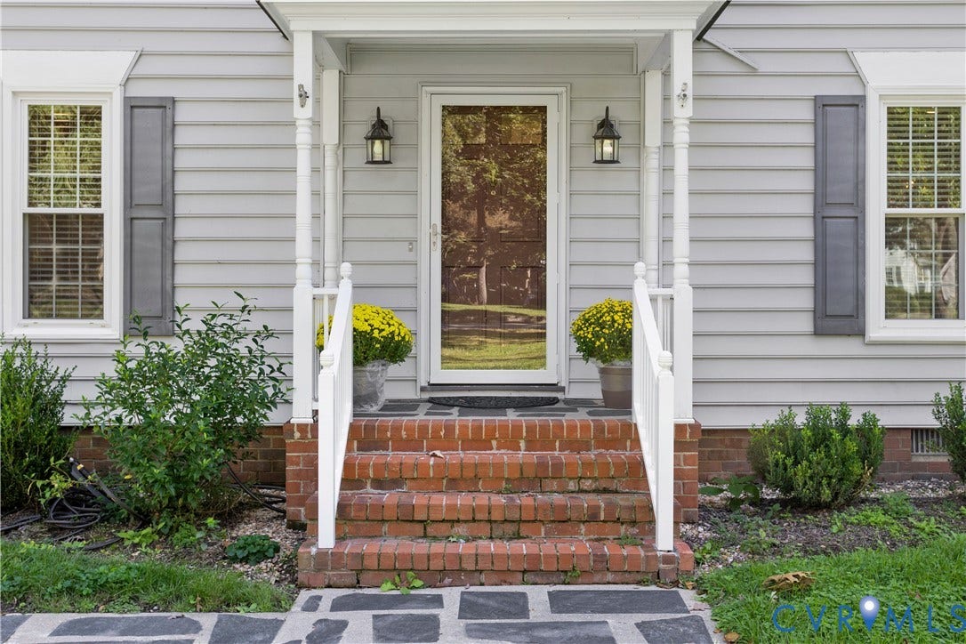 327 Huddersfield Drive, Chesterfield, VA 23236 Front entrance featuring horizontal siding, shutters, brick steps with white railings, and wall-mounted lanterns