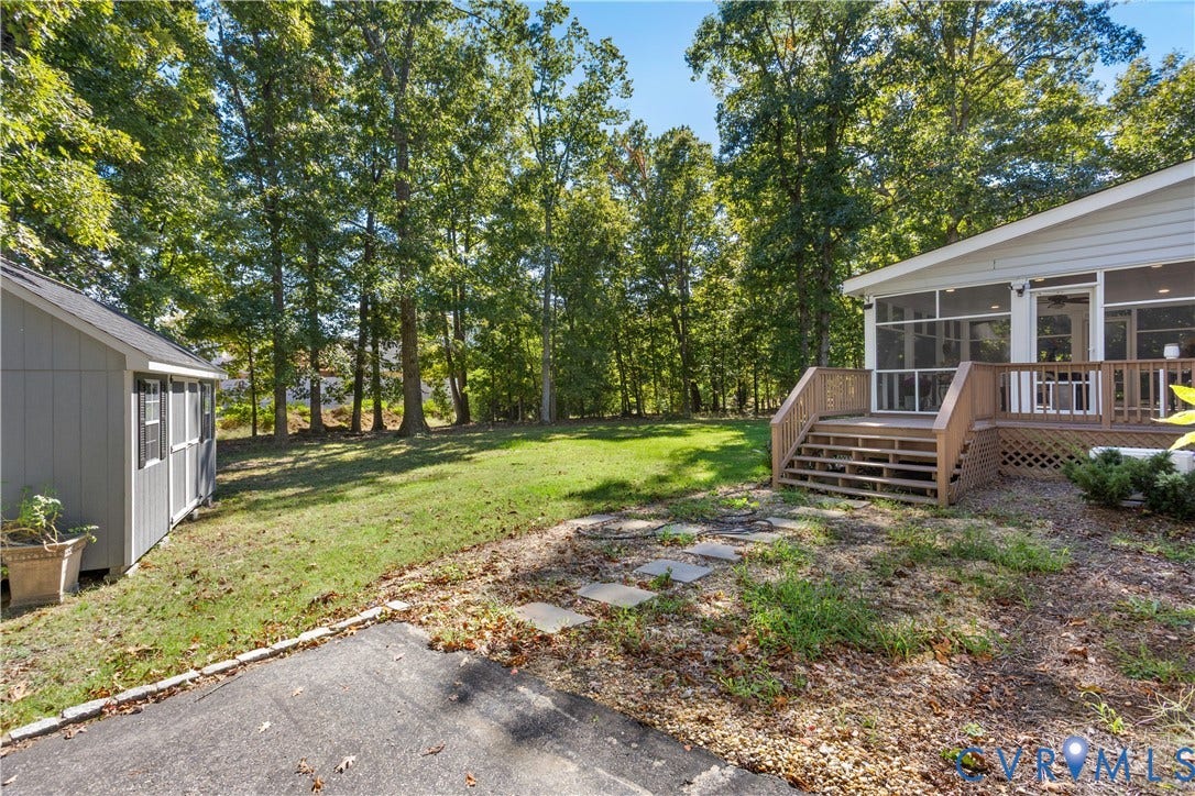 327 Huddersfield Drive, Chesterfield, VA 23236 Rear exterior featuring a screened-in porch with wood-tone decking, a detached storage shed, stepping stone path, and a grass-covered backyard framed by mature trees