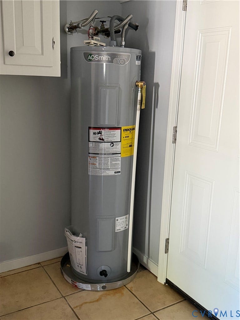 6149 Thierry Street, North Chesterfield, VA 23234 AO Smith water heater featuring a cylindrical metal tank, pressure relief valve, and a protective drain pan, positioned on ceramic tile flooring