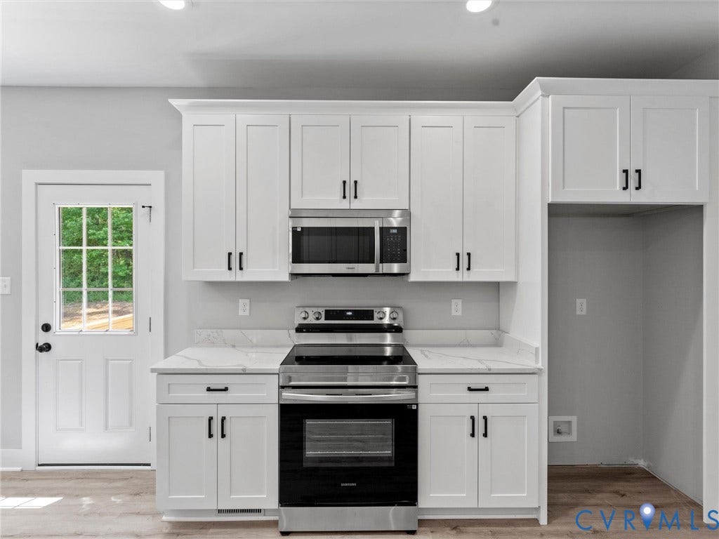 5951 Pot Rock Lane, Pot Rock Ln, Jetersville, VA 23083 White Shaker-style cabinetry, stone-finish countertops, stainless steel appliances, and wood-finish flooring, featuring a single-light exterior door