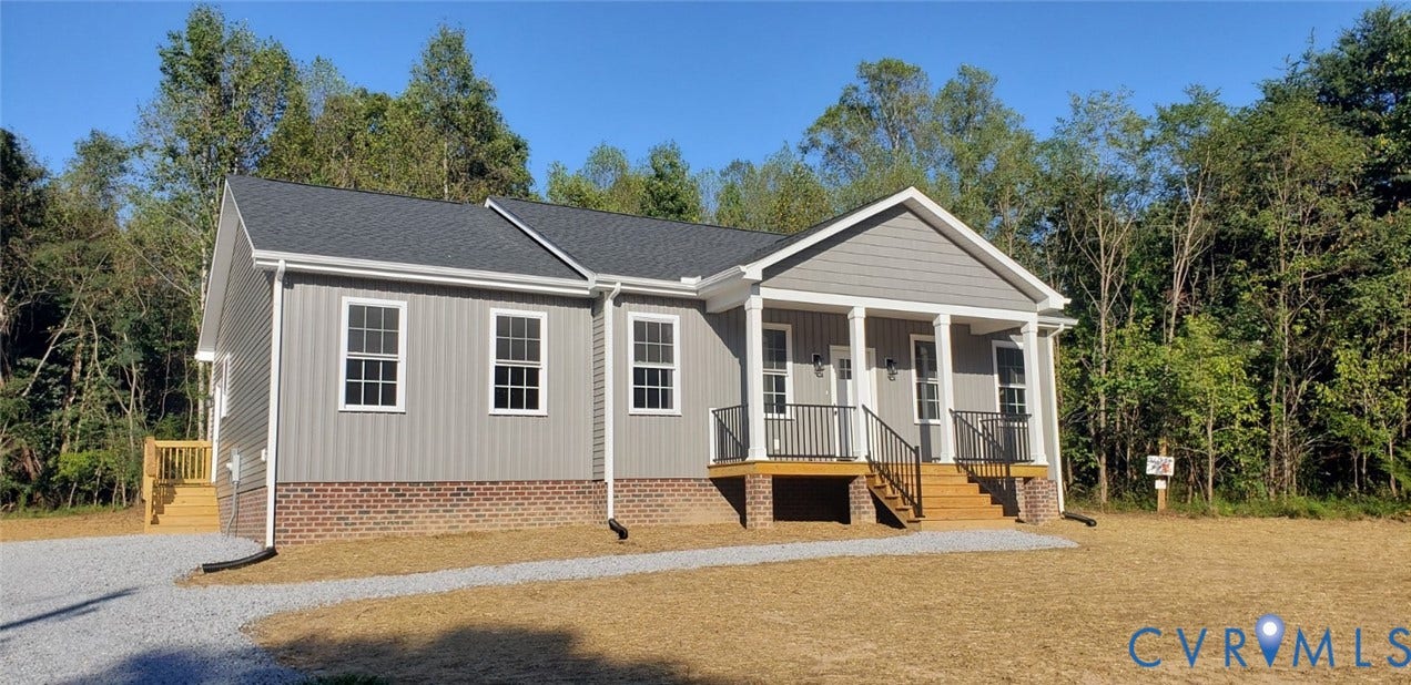 5951 Pot Rock Lane, Pot Rock Ln, Jetersville, VA 23083 Single-story residence featuring gray vertical siding, a brick foundation, a covered front porch with columns, a metal railing, and a gravel driveway