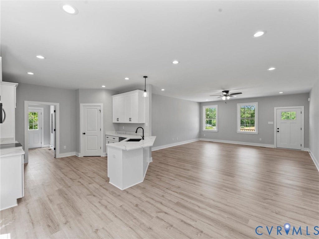 5951 Pot Rock Lane, Pot Rock Ln, Jetersville, VA 23083 Open-concept interior featuring light-toned wood-finish flooring, recessed lighting, white cabinetry, a kitchen island with a dark faucet, and multi-pane exterior doors