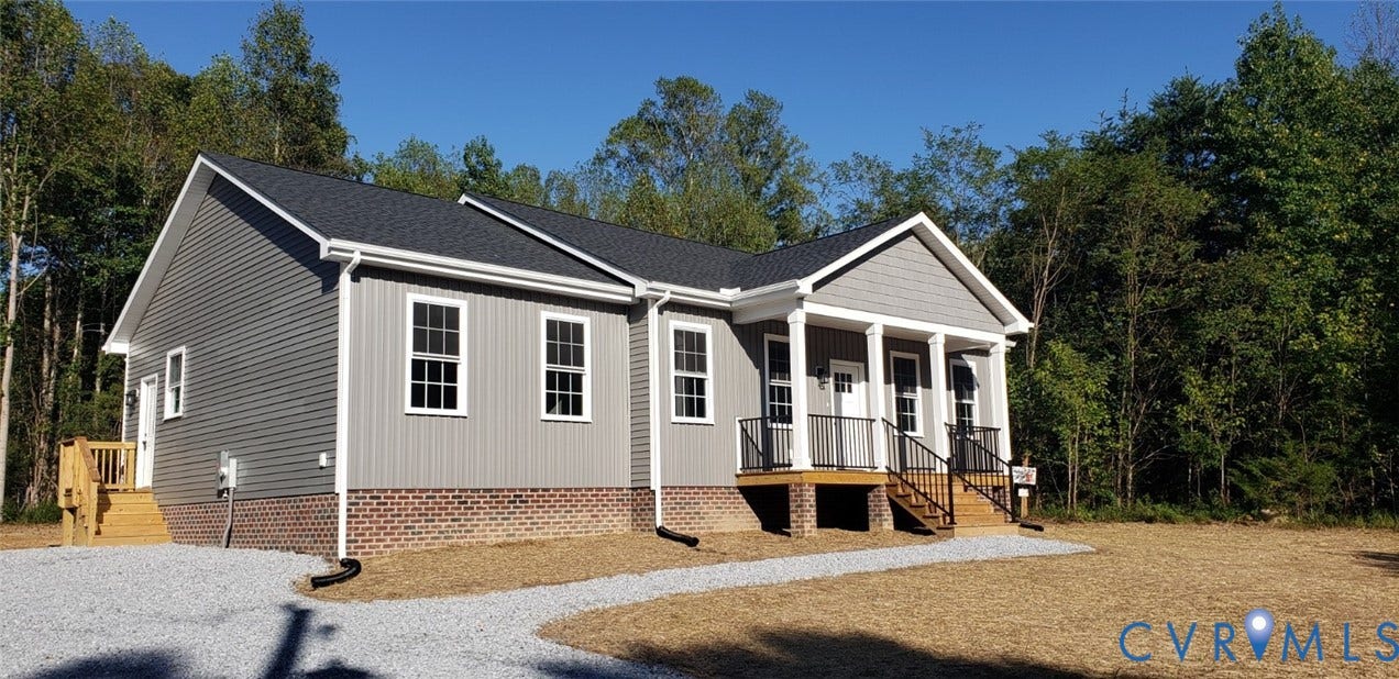 5951 Pot Rock Lane, Pot Rock Ln, Jetersville, VA 23083 Single-story residence featuring gray vinyl siding, a brick foundation, a covered front porch with white columns, black metal railings, and a gravel driveway