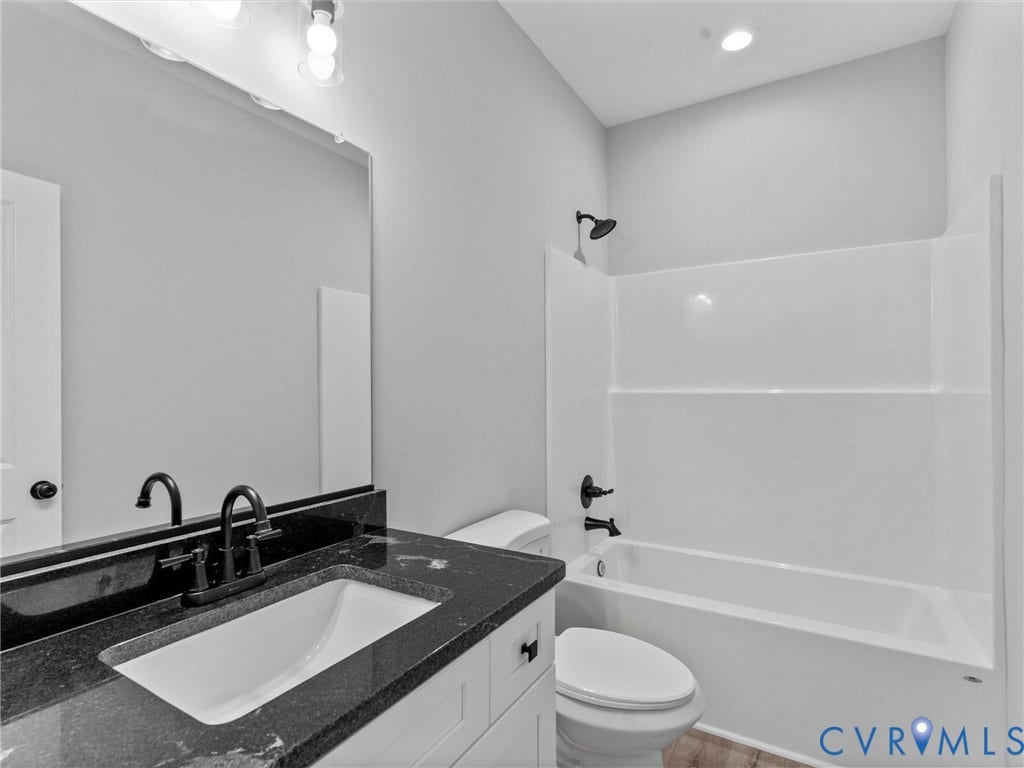 5951 Pot Rock Lane, Pot Rock Ln, Jetersville, VA 23083 Bathroom featuring a white vanity with a dark stone countertop, undermount sink, large wall-mounted mirror, and matte black fixtures throughout, including a tub-shower combination