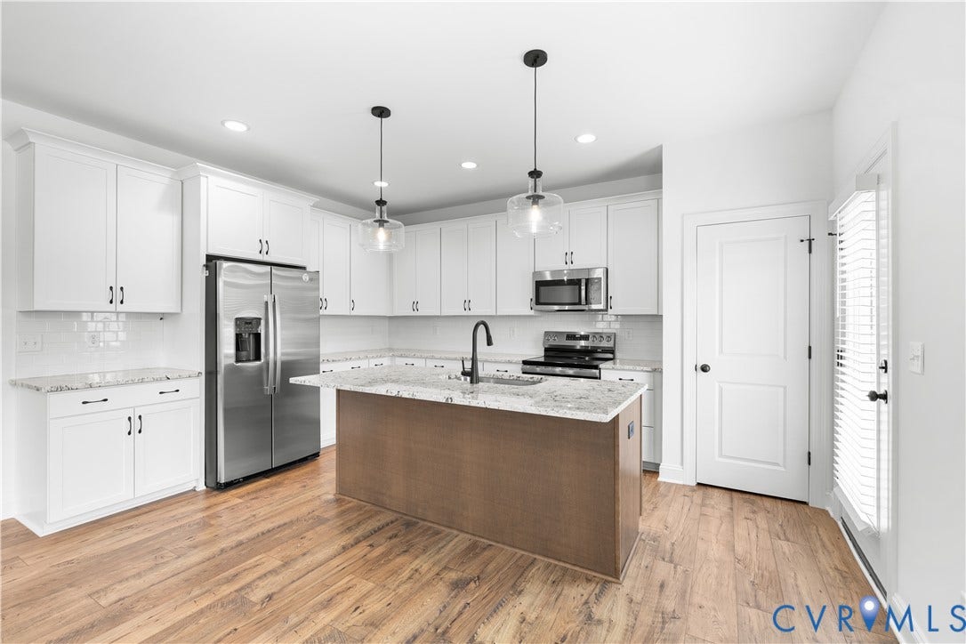 652 Overby Bend Road, Highland Grove, Richmond, VA 23222 Modern kitchen featuring white shaker cabinetry, stainless steel appliances, a wood-finish island with a stone countertop, and wood-finish flooring