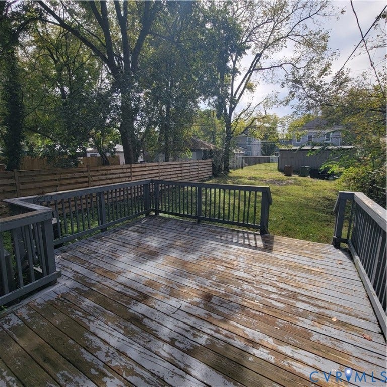 Elevated wood deck with perimeter railing and horizontal wood-slat privacy fencing