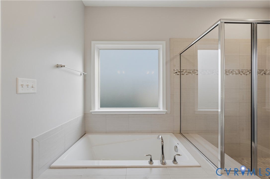 11936 Helmway Court, Chester, VA 23839 Downstairs Primary bathroom. Built-in soaking tub with chrome fixtures, tiled tub surround, and a glass-enclosed shower with mosaic tile inlay