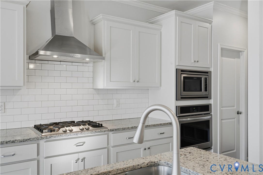 11936 Helmway Court, Chester, VA 23839 Kitchen featuring white shaker-style cabinetry, stone countertops, a subway tile backsplash, a stainless steel gas cooktop with a matching overhead vent hood, and built-in stainless steel double wall ovens