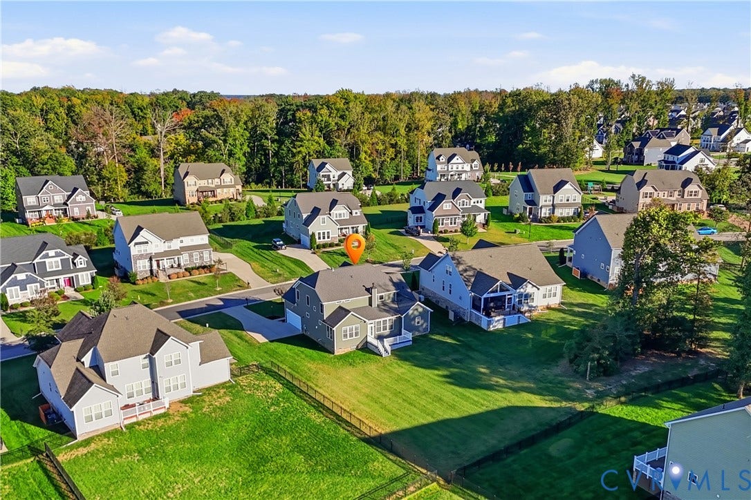 11936 Helmway Court, Chester, VA 23839 Aerial perspective of a multi-story residence featuring a shingled roof, attached garage, rear deck, and an expansive lawn with fencing