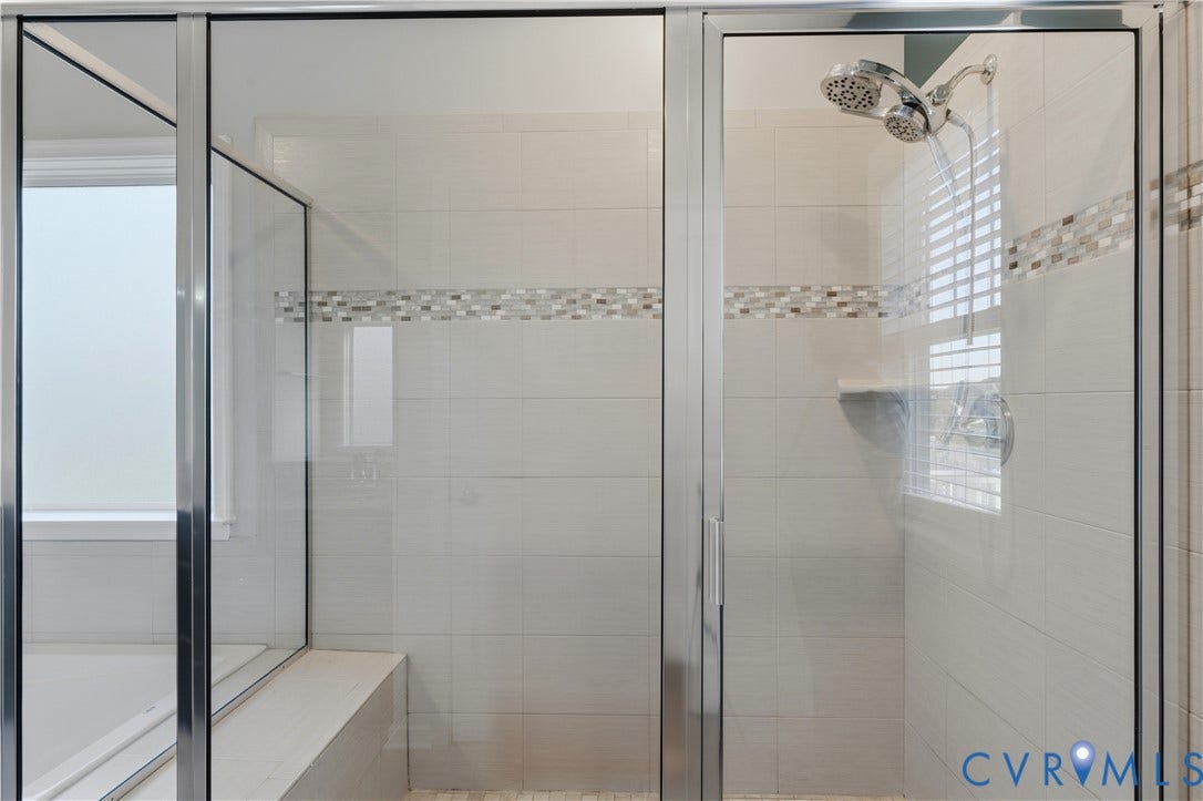 11936 Helmway Court, Chester, VA 23839 Downstairs Primary bathroom. Walk-in shower featuring a chrome-framed glass enclosure, floor-to-ceiling tile, decorative mosaic tile accent border, built-in corner shelving, and a multi-setting showerhead