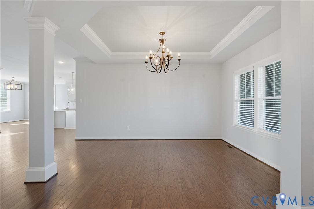 11936 Helmway Court, Chester, VA 23839 Open floor plan featuring wood-finish flooring, tray ceiling, architectural columns, and a central multi-arm chandelier