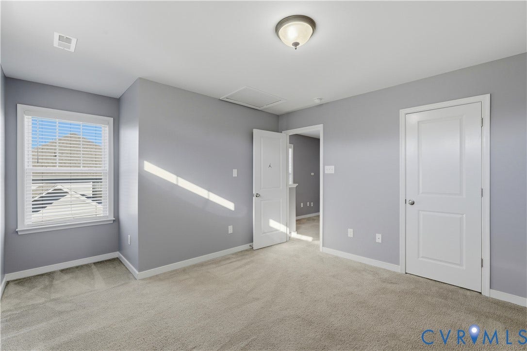 11936 Helmway Court, Chester, VA 23839 Bedroom #4 Neutral-toned interior space featuring neutral wall-to-wall carpeting, white two-panel interior doors, a multi-pane window with white trim, and a flush-mount ceiling light fixture