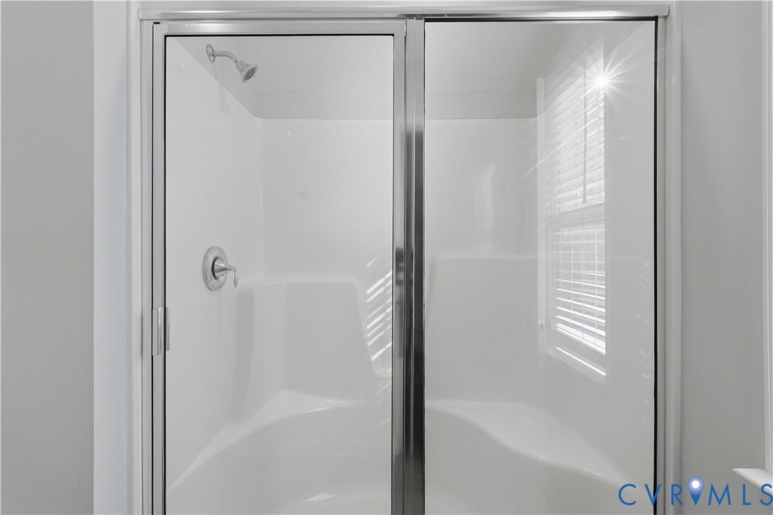 11936 Helmway Court, Chester, VA 23839 Upstairs Primary Walk-in shower enclosure featuring a white seamless surround, integrated seating, polished chrome hardware, and a semi-frameless glass door