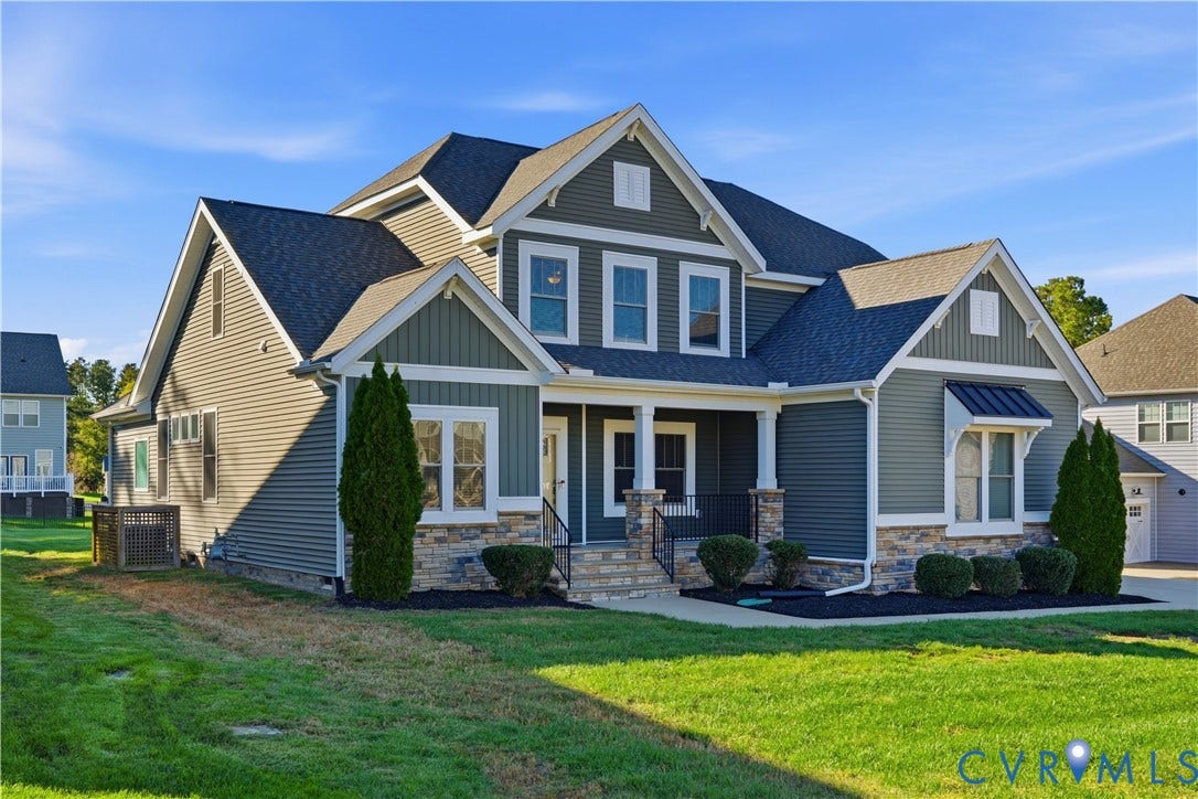 11936 Helmway Court, Chester, VA 23839 Two-story exterior featuring dark lap siding, stone veneer foundation, metal shed roof accent, a covered front porch with square columns, and multi-gabled roofline