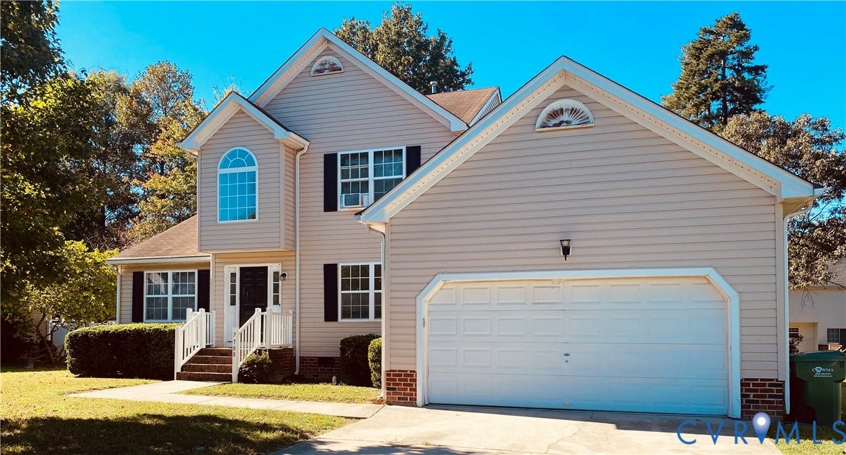 7708 Shoveler Drive, Henrico, VA 23231 Two-story exterior featuring light-toned vinyl siding, a front-facing attached two-car garage, brick foundation detailing, an arched transom window, and a raised front entryway with white railings