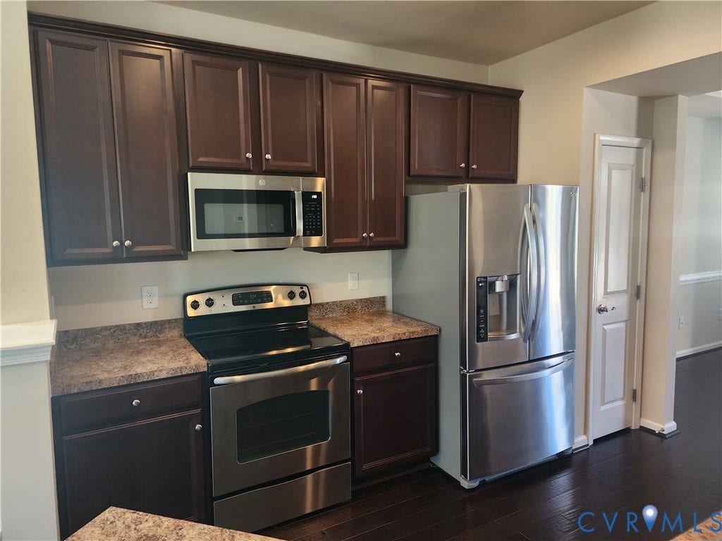 9031 Annex Lane, Mechanicsville, VA 23116 Dark wood-finish cabinetry, stainless steel appliances, speckled laminate countertops, and dark wood-finish flooring