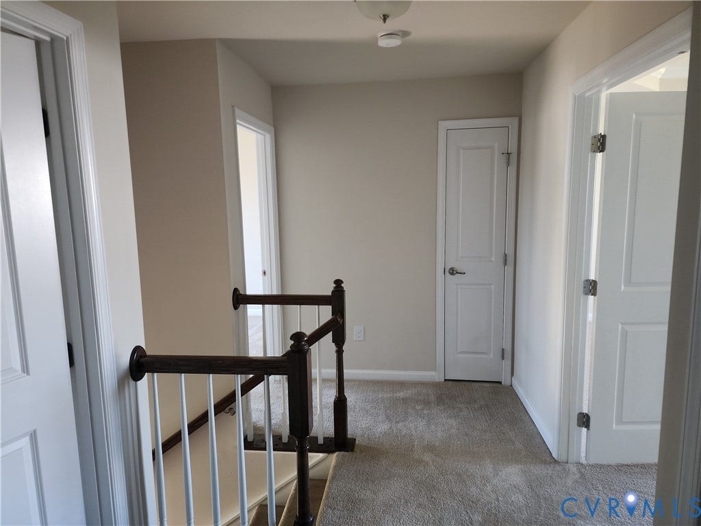 9031 Annex Lane, Mechanicsville, VA 23116 Hallway featuring neutral wall tones, wall-to-wall carpeting, white two-panel interior doors, and a wood-finish handrail with white balusters