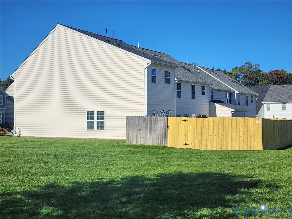 9031 Annex Lane, Mechanicsville, VA 23116 Exterior featuring light-colored horizontal siding, asphalt shingle roof, double-hung windows, and a fenced backyard with a grass lawn