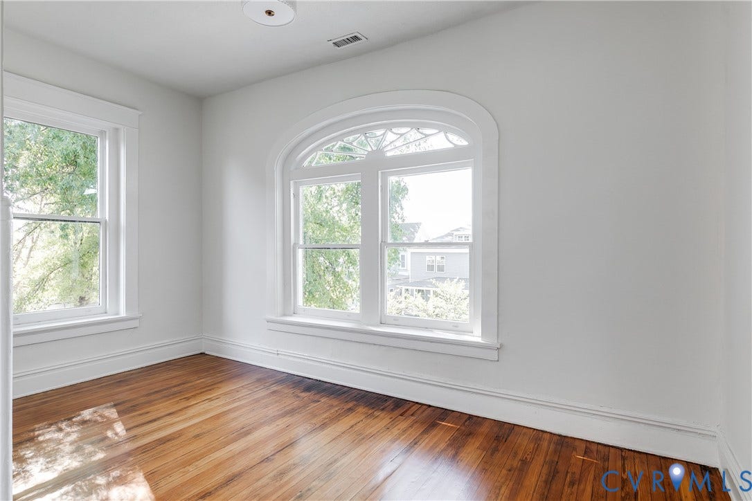 2005 Barton Avenue, Barton Heights, Richmond, VA 23222 Room featuring wood-finish flooring, a prominent arched window with decorative transom, and a secondary rectangular window with wide white trim