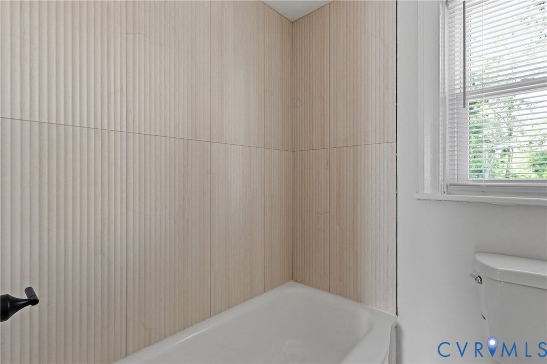 7406 Alycia Avenue, Henrico, VA 23228 Bathtub with textured wall tiling and an adjacent window with blinds
