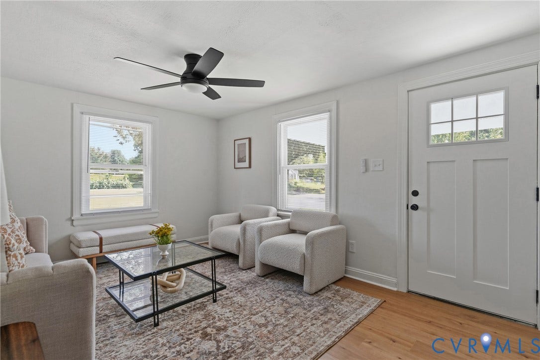 7406 Alycia Avenue, Henrico, VA 23228 Wood-finish flooring, white paneled door with glass inserts, two windows with white trim, ceiling fan with integrated lighting, and light-colored walls