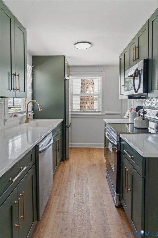 7406 Alycia Avenue, Henrico, VA 23228 Galley kitchen featuring green cabinetry, gold-tone hardware, stainless steel appliances, light countertops, and wood-finish flooring