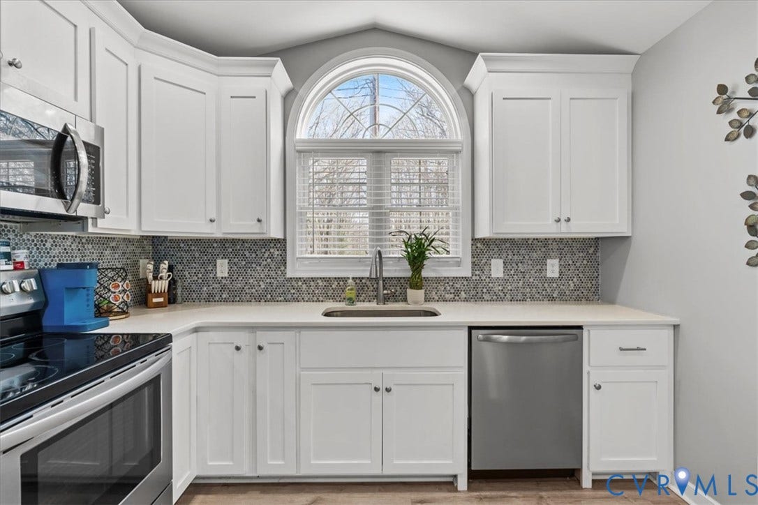 600 Highland Avenue, Hopewell, VA 23860 Kitchen featuring white shaker cabinetry, arched window with muntin detailing, stainless steel appliances, apron-front sink, and circular mosaic tile backsplash