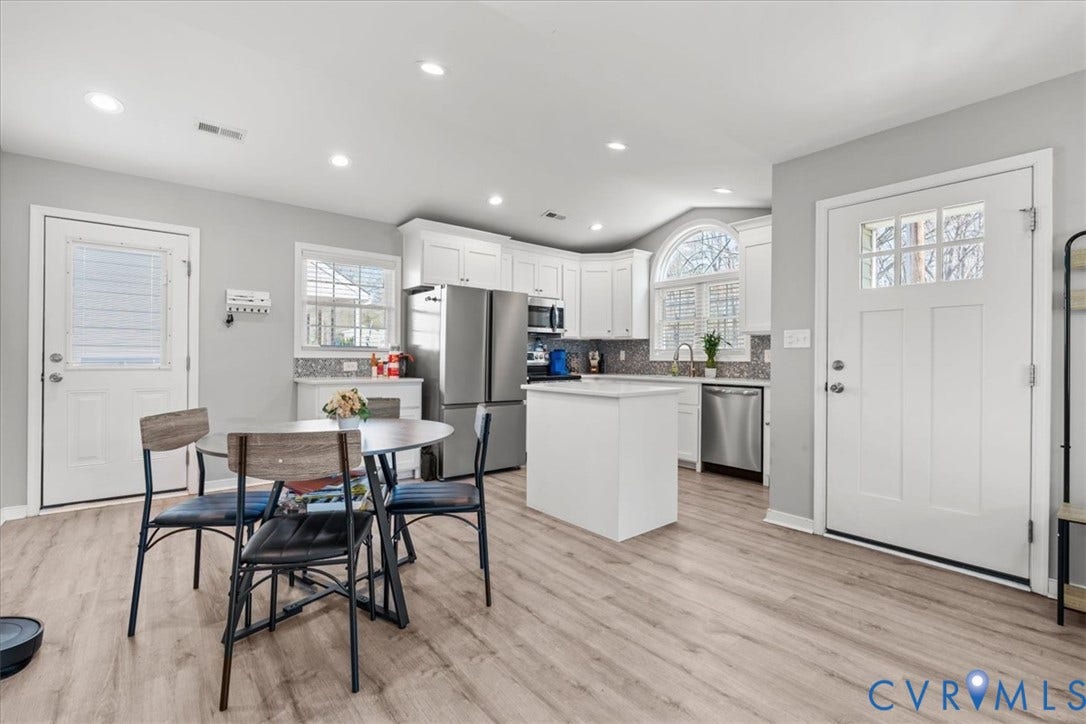 600 Highland Avenue, Hopewell, VA 23860 Kitchen featuring white cabinetry, stainless steel appliances, a central island with a solid-surface countertop, arched window, and wood-finish flooring