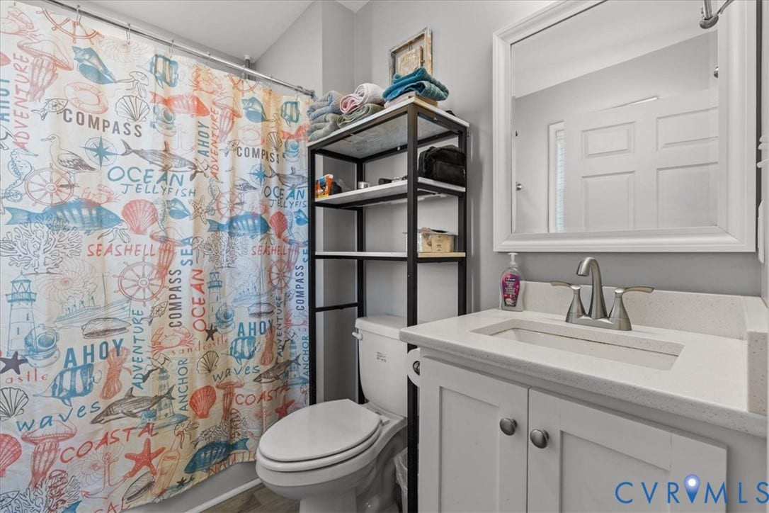 600 Highland Avenue, Hopewell, VA 23860 Bathroom featuring a white vanity cabinet, solid-surface countertop with an integrated rectangular sink, dual-handle metal faucet, and a large wall-mounted mirror with a white frame