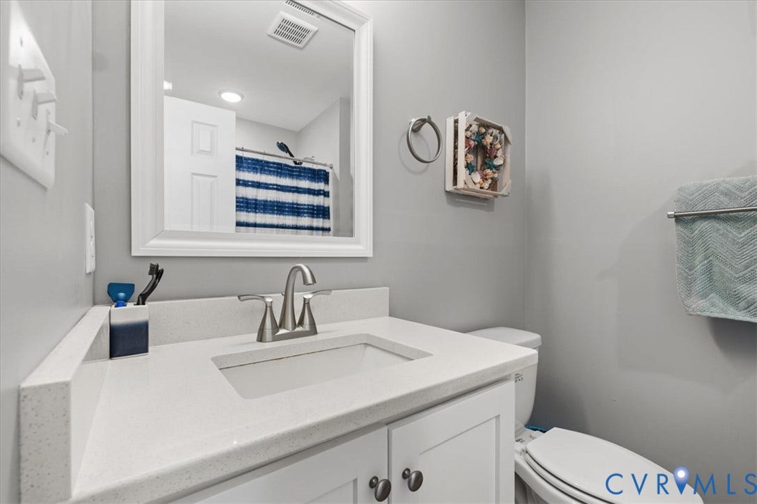 600 Highland Avenue, Hopewell, VA 23860 White vanity cabinet featuring a quartz countertop with an integrated rectangular sink and brushed nickel faucet, paired with a framed wall mirror