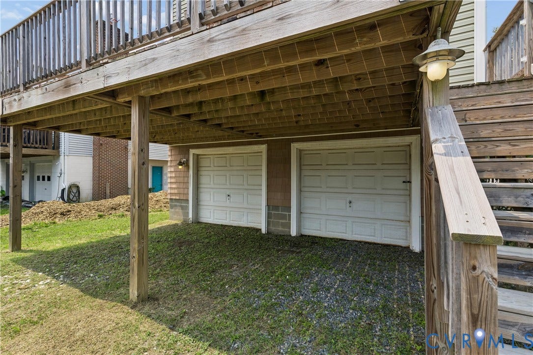 11 Bonita Drive, Hampton, VA 23664 Two-car garage featuring paneled doors and an exterior wooden deck with a staircase