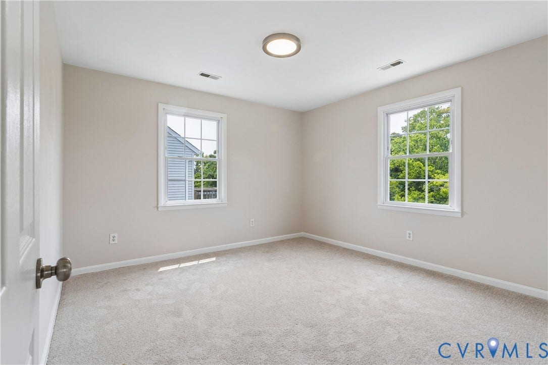 11 Bonita Drive, Hampton, VA 23664 Neutral-toned room featuring neutral carpeting, double-hung windows with grid muntins, and a flush-mount circular ceiling fixture