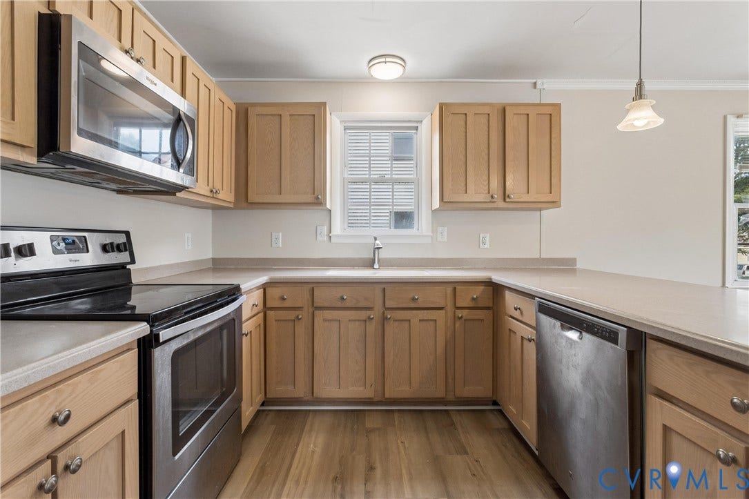11 Bonita Drive, Hampton, VA 23664 Kitchen featuring light-finish cabinetry, neutral solid-surface countertops, stainless steel appliances, wood-finish flooring, and a pendant light fixture