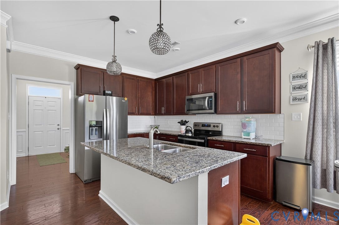 2230 Nightfall Drive, Chesterfield, VA 23236 Kitchen featuring wood-finish cabinetry, stone countertops, a center island with a dual-basin sink, subway tile backsplash, and decorative pendant lighting