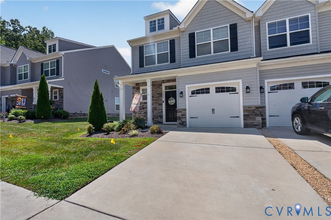 2230 Nightfall Drive, Chesterfield, VA 23236 Multi-level townhome featuring horizontal lap siding, stone veneer accents, multi-pane windows with dark shutters, and attached two-car garages with arched-top detailing