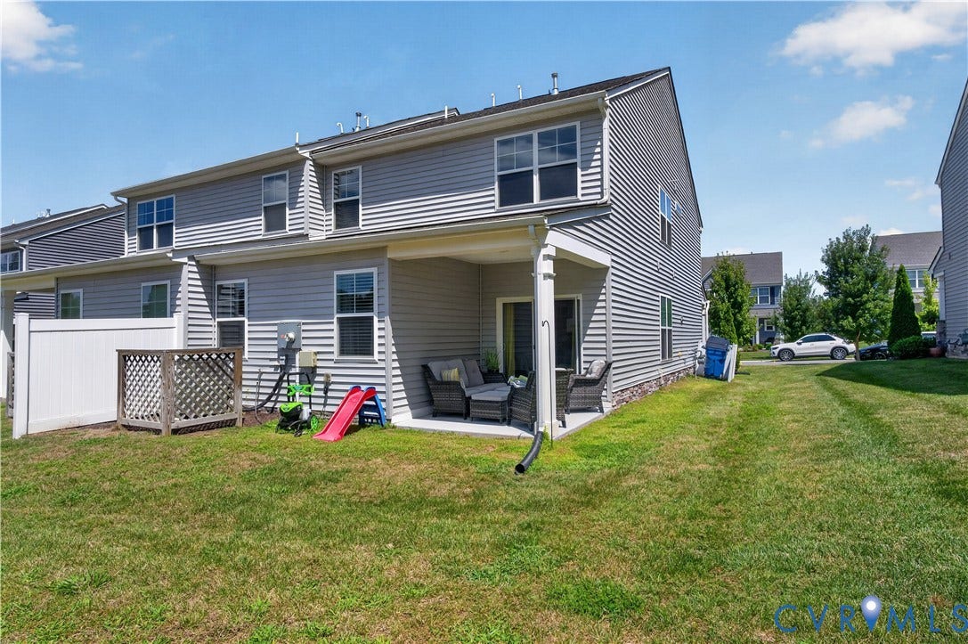 2230 Nightfall Drive, Chesterfield, VA 23236 Multi-level residence featuring horizontal vinyl siding, a covered concrete patio, and a white privacy fence enclosing a portion of the yard