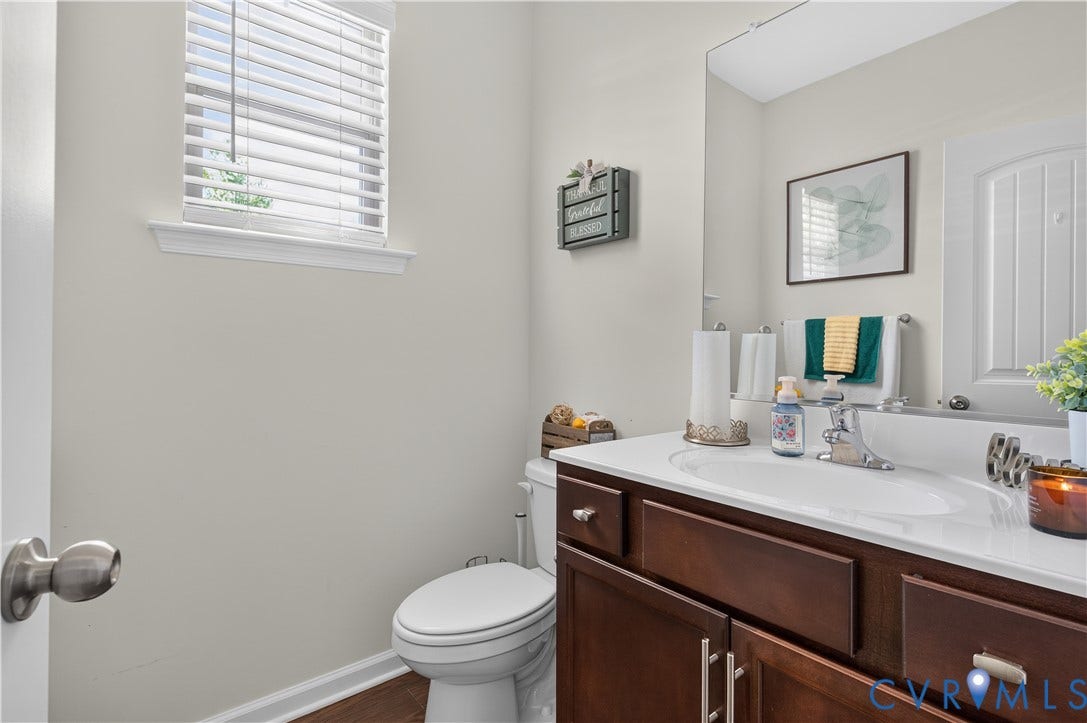 2230 Nightfall Drive, Chesterfield, VA 23236 Bathroom featuring a dark wood-finish vanity, solid-surface countertop with an integrated basin, wall-mounted mirror, and wood-finish flooring