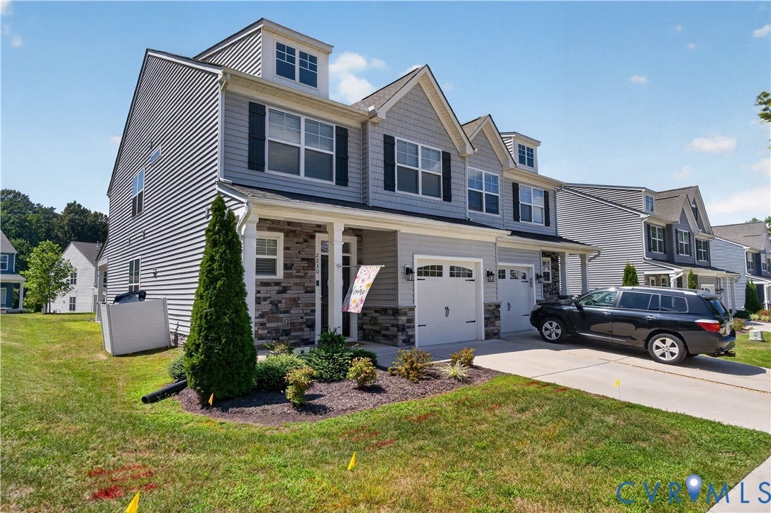 2230 Nightfall Drive, Chesterfield, VA 23236 Multi-level residence featuring gray vinyl siding, stone veneer accents, dormer windows, and a double-bay garage with carriage-style doors