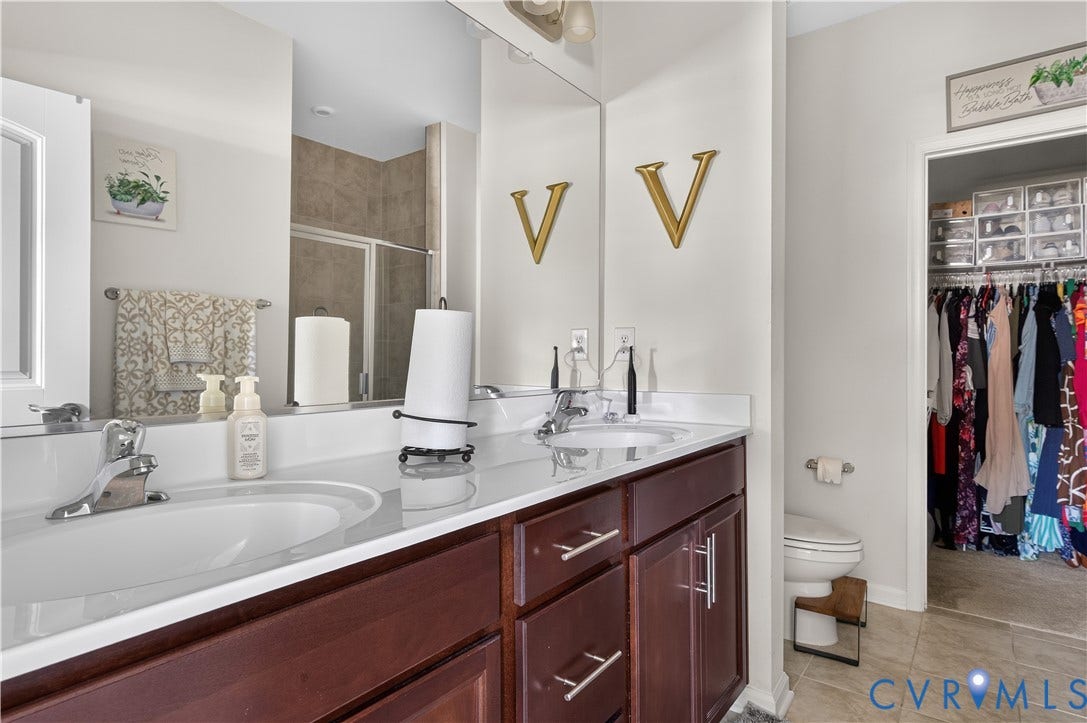 2230 Nightfall Drive, Chesterfield, VA 23236 Double vanity featuring dark wood cabinetry, a light-toned countertop, dual inset sinks, polished chrome hardware, and an expansive wall-mounted mirror